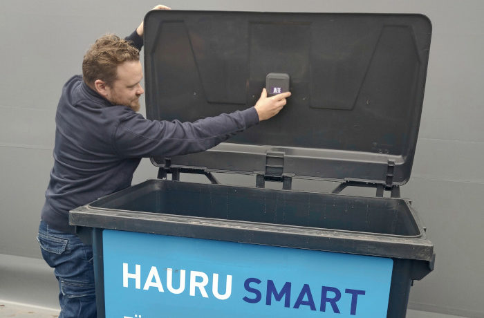Innostunut mies kiinnittää sensoria jäteastiaan, jossa lukee Hauru Smart.